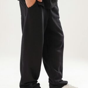 A person wearing casual black lounge pants paired with stylish white sneakers on a plain background.